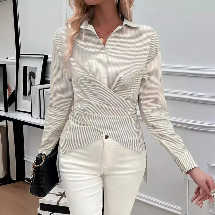 La chemise asymétrique à manches longues à rayures verticales bleues et blanches pour femmes comprend un design torsadé distinctif et à la mode